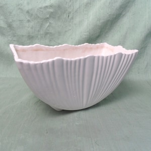 May include: White ceramic planter with a scalloped edge and a fluted design. The planter has a rectangular shape and a wide base.