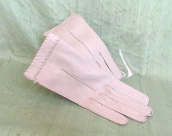 May include: A pair of pink leather gloves with a stitched design. The gloves are folded in half and have a white tag attached.