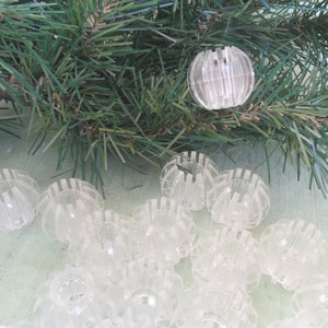 May include: A close-up of a group of clear plastic baubles with a ribbed design. The baubles are arranged in a circle on a light green surface.