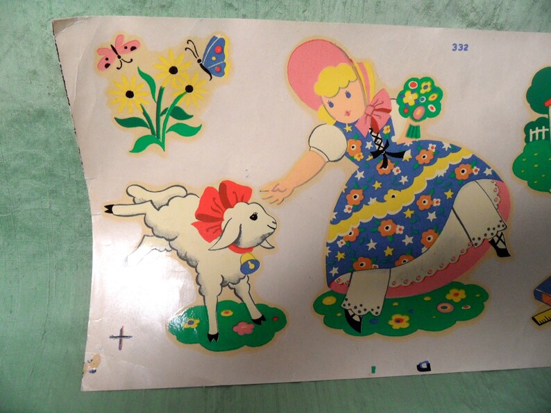 May include: A vintage illustration of a girl in a pink and blue dress holding a bouquet of flowers and a white lamb with a red bow. The illustration is on a white background with a green border.