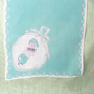 Può includere: Un fazzoletto vintage con sfondo verde acqua chiaro e bordo smerlato bianco ornato da piccoli disegni floreali. Il centro presenta un'illustrazione dettagliata di un bambino in un ovale bianco con un fiocco. Il bambino indossa un cappello, un maglione e pantaloni.