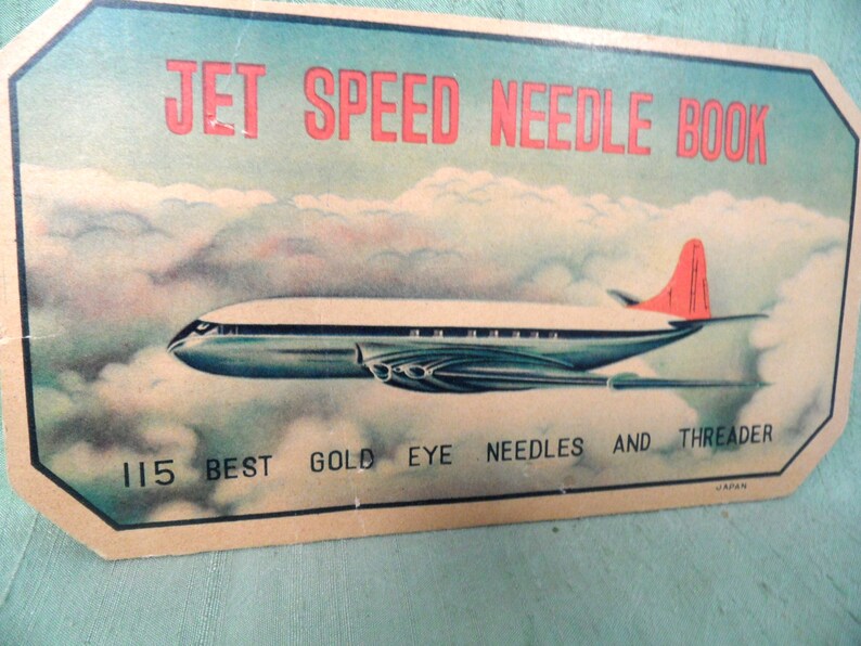 May include: Vintage packaging for a needle book featuring a blue and silver airplane flying through clouds. The text reads "Jet Speed Needle Book 115 Best Gold Eye Needles and Threader Japan".