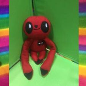Puede incluir: Tres peluches con forma de perezosos, cada uno con un disfraz de superhéroe diferente. El primer perezoso lleva un disfraz de Flash rojo y amarillo. El segundo perezoso lleva un disfraz de Deadpool rojo y negro. El tercer perezoso lleva un disfraz de Spiderman rojo y azul.