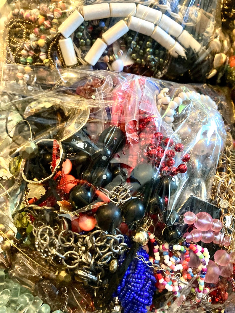 Peut inclure: Un grand sac en plastique rempli d'une vari&eacute;t&eacute; de bijoux color&eacute;s, y compris des perles, des cha&icirc;nes et des pendentifs. Les bijoux sont un m&eacute;lange de diff&eacute;rents mat&eacute;riaux, notamment du m&eacute;tal, du plastique et du verre.