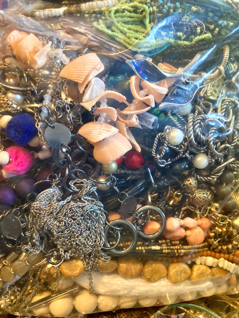 Peut inclure: Un sac en plastique rempli d'une vari&eacute;t&eacute; de bijoux, y compris des colliers, des bracelets, des boucles d'oreilles et des perles. Les bijoux sont faits de diff&eacute;rents mat&eacute;riaux, notamment du m&eacute;tal, du plastique et du bois. Le sac est rempli de diff&eacute;rentes couleurs, notamment l'or, l'argent, le noir, le blanc, le bleu, le vert et le rouge.