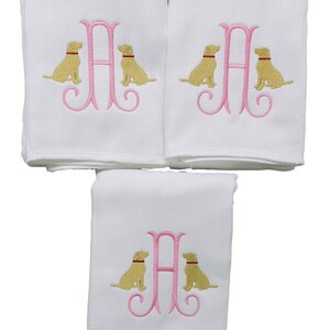 Baby girl burp cloth with a pink initial surrounding on either side with embroidered yellow lab dogs.