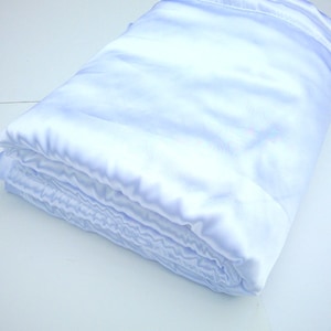 May include: A light blue satin blanket folded neatly. The blanket is soft and smooth, and it would be perfect for a baby or child.