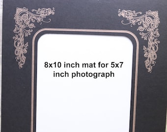 May include: Black picture frame mat with a gold ornate design. The mat is 8x10 inches and fits a 5x7 inch photograph.