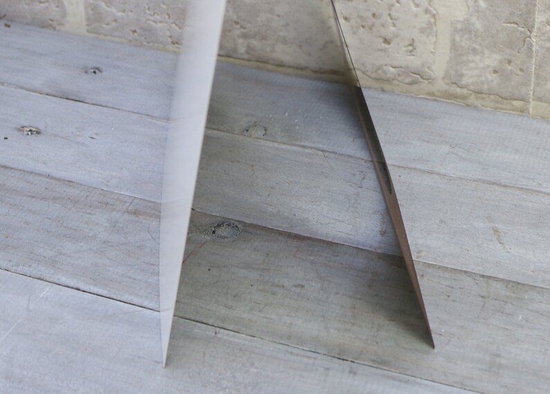 May include: A white card with a silver edge is standing upright on a light wood surface.