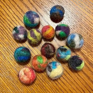 May include: A collection of 14 colourful felt balls, each with a unique pattern. The balls are various shades of blue, green, red, yellow, and brown.