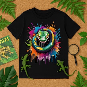 Puede incluir: Camiseta negra con una vibrante ilustración de una serpiente. La serpiente, con escamas verdes, amarillas y azules, está enroscada sobre un fondo de salpicaduras de pintura coloridas. También se ven dos lagartos verdes y un libro con la palabra "TILES".
