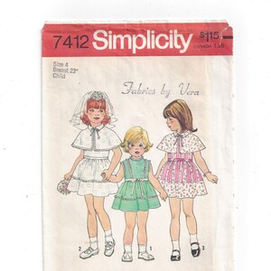May include: Simplicity sewing pattern number 7412 for a child's dress. The pattern includes three different styles: a white dress with a cape, a green dress with a ruffle, and a pink and white striped dress. The pattern is titled "Fabrics by Vera".
