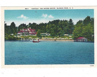 May include: A vintage postcard featuring a photo of a large house with a red roof on a lake. The house is surrounded by trees and there is a small boat in the water. The text on the postcard reads "BR-3 "CHETOLA" THE SNYDER ESTATE, BLOWING ROCK, N. C."