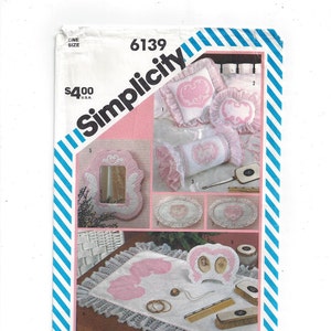 May include: Simplicity sewing pattern number 6139 for a set of pink and white embroidered home decor items. The pattern includes instructions for making a pillow, a bolster, a mirror frame, a tray, and a picture frame. The pattern is priced at $4.00.