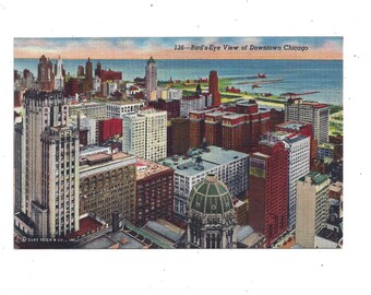 May include: A vintage postcard depicting a bird's-eye view of downtown Chicago. The postcard shows a cityscape with tall buildings, including the iconic Wrigley Building, and a body of water in the background. The text on the postcard reads "126 - Bird's-Eye View of Downtown Chicago."