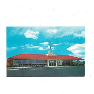 May include: A red brick building with a white steeple and a sign that reads "The Golden Rule". The building has large windows and a flat roof. The sky is blue with white clouds.