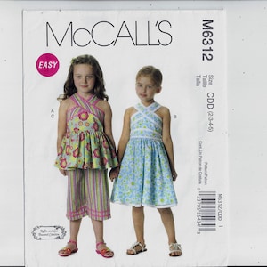 May include: McCall's sewing pattern for a girl's dress and pants. The pattern is labeled "Easy" and includes sizes 2-3-4-5. The pattern is for a dress with a criss-cross halter top and a skirt with a floral print. The pants are striped with a floral print top.