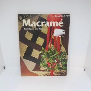 May include: A vintage book titled "Macrame: Techniques and Projects" with a red and orange macrame plant hanger on the cover. The book is a Sunset Book and costs $2.95.