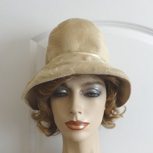May include: A beige velvet hat with a wide brim and a satin ribbon around the crown.