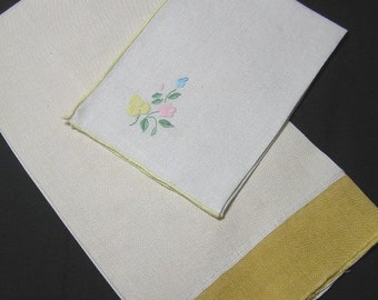 Puede incluir: Dos toallas de té de lino blanco, una con un borde amarillo y la otra con un diseño floral bordado amarillo.