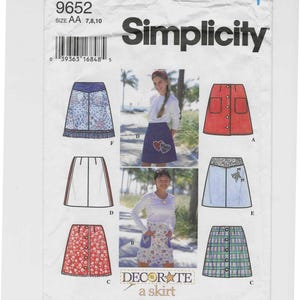 May include: Simplicity sewing pattern 9652 for decorating a skirt. The pattern features various skirt designs, including a red skirt with pockets, a blue skirt with heart appliques, and a plaid skirt. The text "DECORATE a skirt" is also visible.