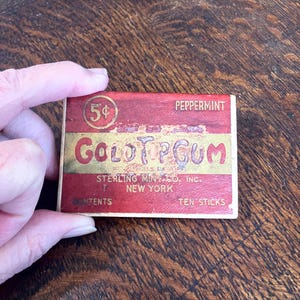 May include: Vintage Gold Tip Gum box with a red and gold design. The box reads "5¢" and "Peppermint." The text "Gold Tip Gum" is in gold lettering. The box is from Sterling Mint Co. Inc., New York.