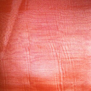 May include: A close-up of a red fabric with a subtle shimmer and a textured surface.