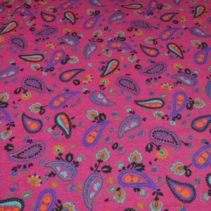 May include: Pink fabric with a paisley pattern in shades of blue, orange, and black.