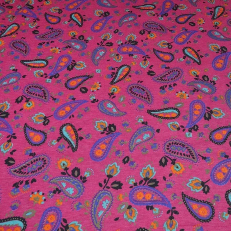 May include: Pink fabric with a paisley pattern in shades of blue, orange, and black.