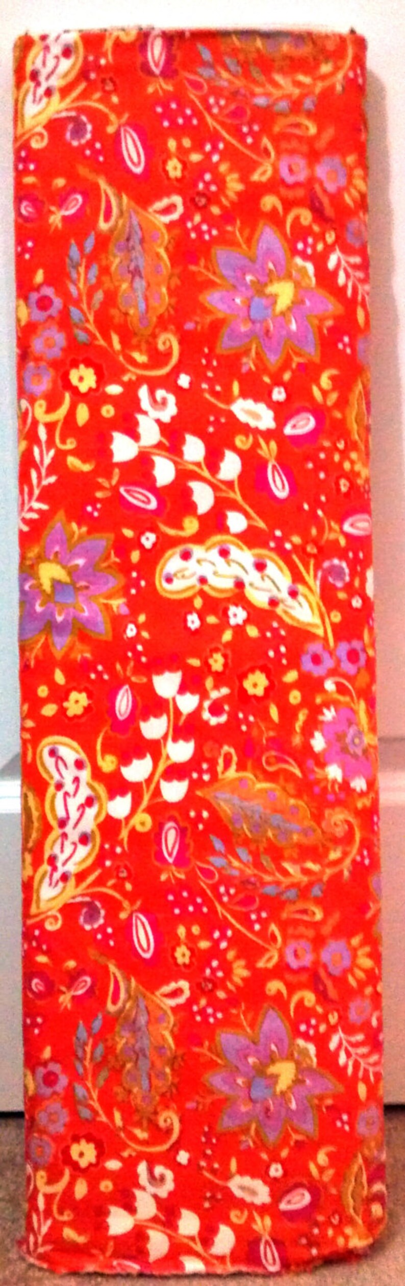 May include: Red fabric with a paisley pattern in shades of orange, yellow, white, pink, and purple.