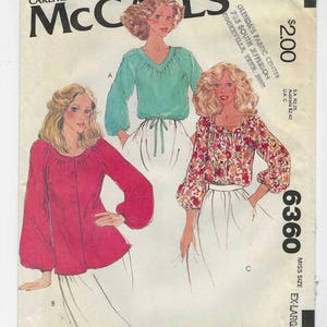 May include: Vintage McCall's sewing pattern showing three blouse designs. The pattern includes a red button-down blouse, a teal V-neck blouse, and a floral print square-neck blouse. The pattern is size extra large.