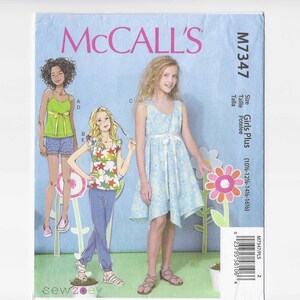 May include: A McCall's sewing pattern for Girls Plus sizes. The pattern features illustrations of girls in various outfits, including a dress, top, and shorts. The pattern is on a light blue background with the text "McCall's" at the top.