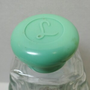 May include: A clear glass bottle with a green plastic lid. The lid has a raised letter "L" on it.