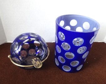 Peut inclure: Un ensemble de deux cendriers en verre bleu cobalt avec un motif de pois blancs. Les cendriers sont en verre et ont une forme ronde. Un cendrier est un bol avec un bord en laiton et l'autre est un cylindre.