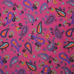 May include: A pink fabric with a paisley pattern in shades of blue, orange, and black.