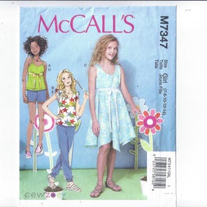 May include: McCall's sewing pattern M7347 for girls' clothing. The pattern features illustrations of girls in various outfits, including a dress, shorts, and tops. The pattern size range is 7-8-10-12-14. The McCall's logo is at the top.