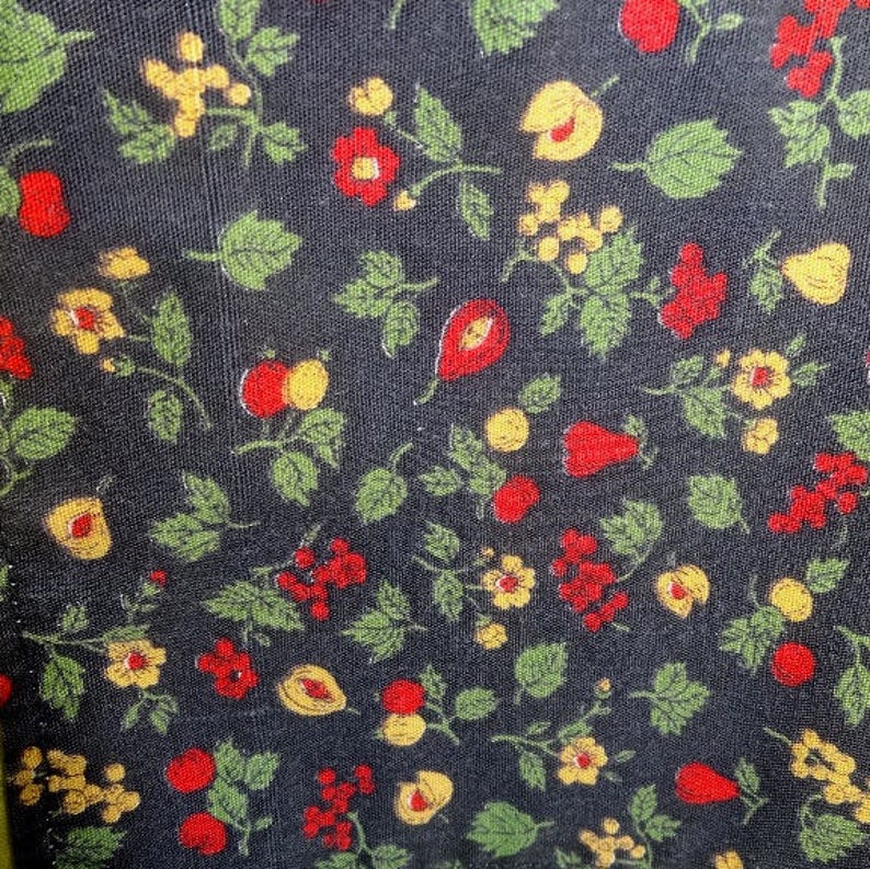 May include: Black fabric with a repeating pattern of red and yellow flowers, green leaves, and small red berries.