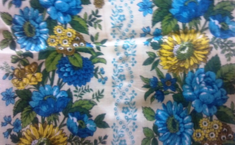 May include: A white fabric with a repeating pattern of blue and yellow flowers. The flowers are stylized and have a vintage look.