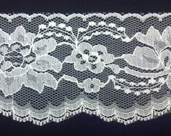 May include: White lace trim with a floral pattern. The lace has a scalloped edge.