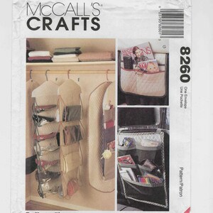 Puede incluir: Un sobre de patrón McCall's Crafts con imágenes de organizadores de armario y soluciones de almacenamiento. El diseño incluye organizadores colgantes para bolsos y un organizador para el asiento del coche. El número 8260 es visible.