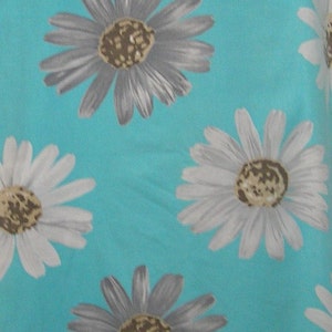 May include: A turquoise fabric with a repeating pattern of white and gray daisies. The daisies have brown centers.