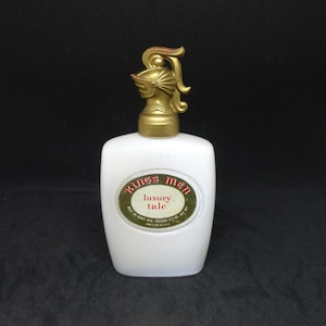 May include: White bottle of Kings Men Luxury Talc with a gold knight helmet shaped stopper. The label is green with red and white text.