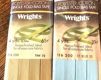 May include: Two packages of Wrights polyester/cotton single fold bias tape. One package is tan, labeled 116 200 TAN 73, and the other is light blue, labeled 116 200 LT. BLUE 52. Each package contains 4 yards of tape for easy-care fabrics.