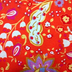 May include: Red fabric with a paisley pattern featuring white, pink, and gold floral designs.
