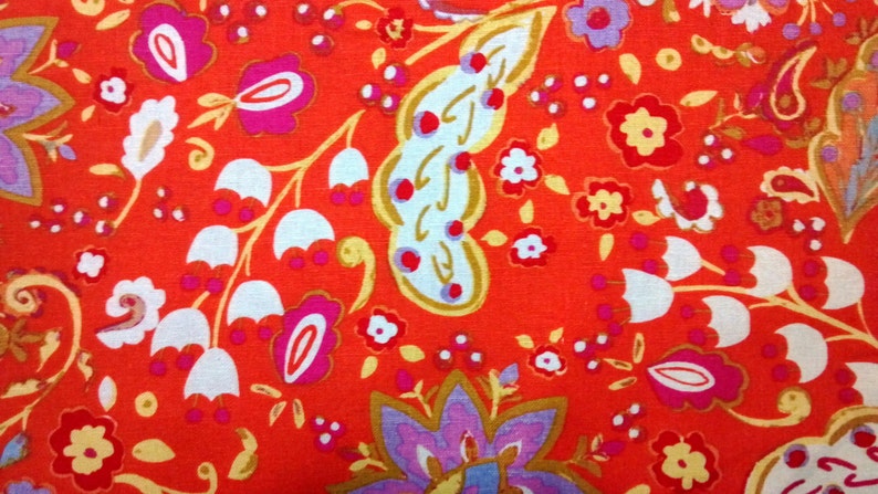 May include: Red fabric with a paisley pattern featuring white, pink, and gold floral designs.