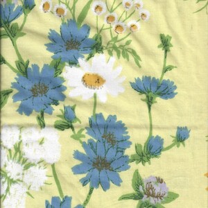 May include: A yellow fabric with a floral pattern featuring blue and white flowers. The flowers are stylized and have a vintage look.