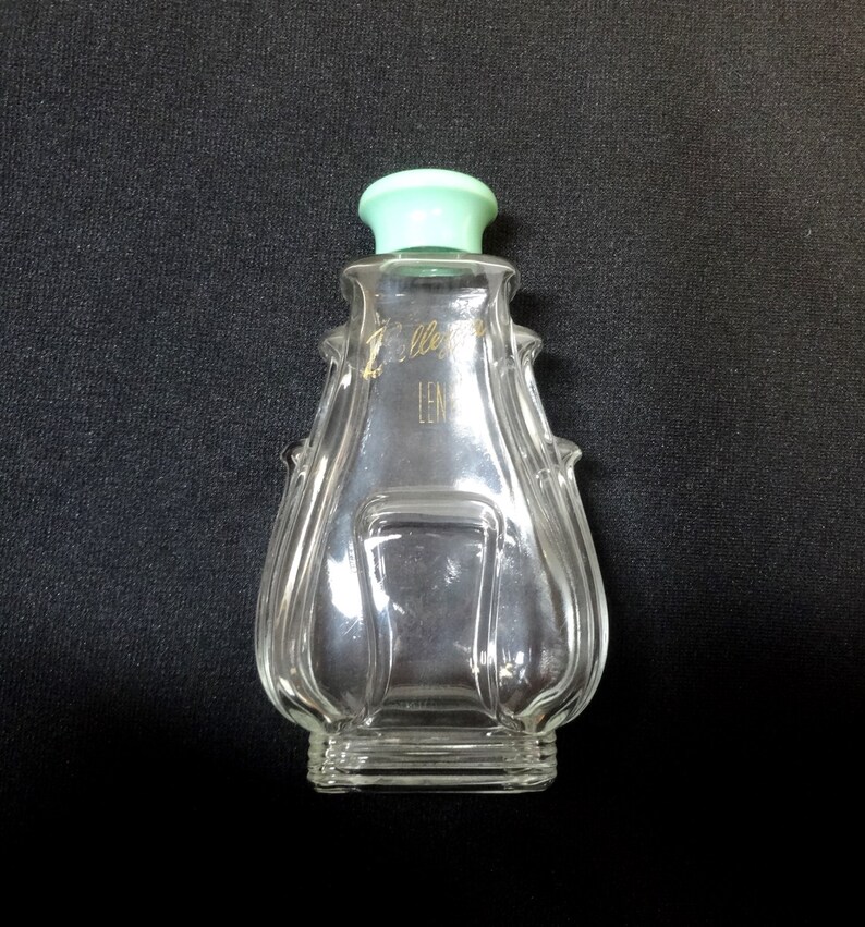 May include: A clear glass bottle with a green plastic lid. The bottle has a unique, textured design and features the text "Jolleys Len"