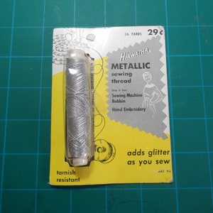May include: A silver metallic sewing thread on a yellow and white card with the text "Hiawatha Metallic sewing thread" and "adds glitter as you sew".