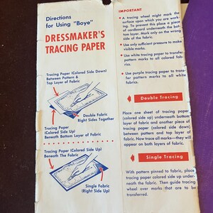 May include: A rectangular instruction sheet for Boye Dressmaker's Tracing Paper with white background, red and blue text, and diagrams illustrating double and single fabric tracing techniques. The paper shows wear along the edges and folds.