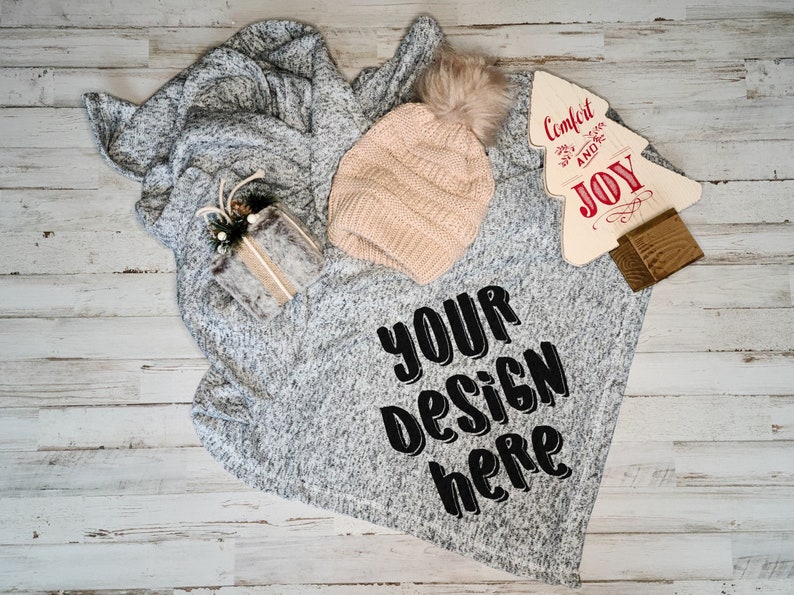 May include: A gray and white fuzzy blanket with a beige knit hat and a wooden sign that says "Comfort and Joy". The blanket has the text "Your Design Here" printed on it.
